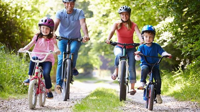 Family of four riding bikes on gravel road